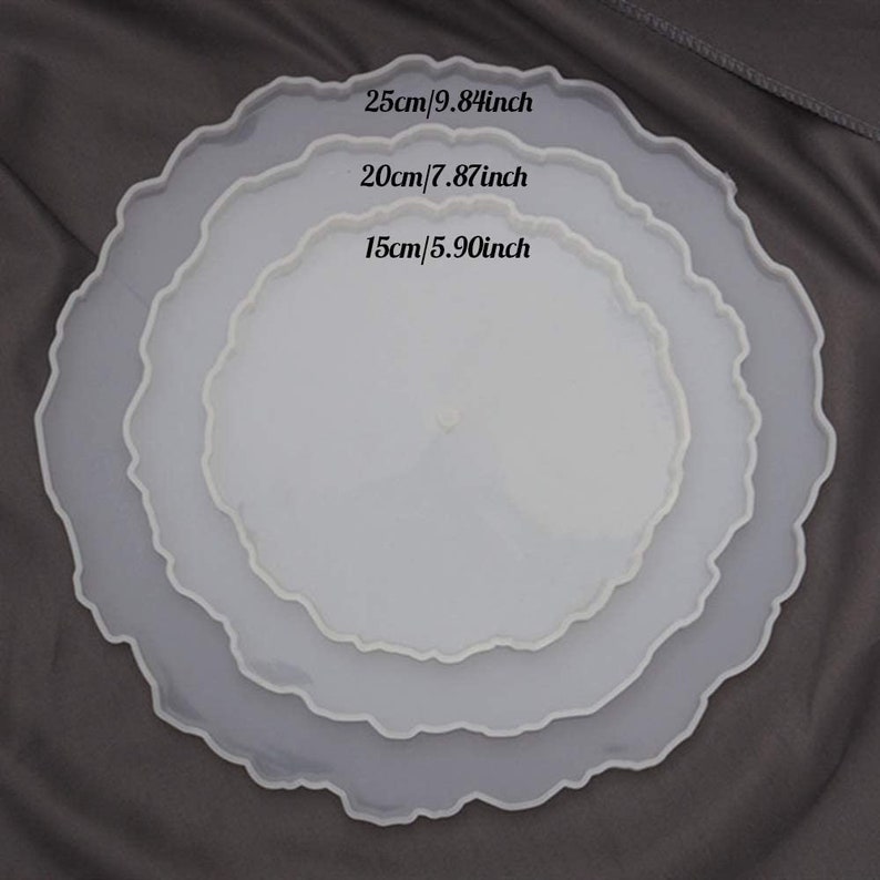 May include: Three white resin trays with a scalloped edge, in descending sizes. The largest tray is 25cm in diameter, the middle tray is 20cm, and the smallest is 15cm. The sizes are also given in inches: 9.84, 7.87, and 5.90.