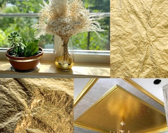 May include: A still-life composition featuring a succulent plant in a brown pot with a gold rim, a bouquet of dried flowers in a clear vase with a gold base, and gold leaf textures. The image also shows a gold ceiling.