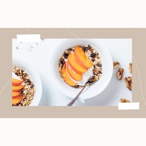 May include: A white bowl filled with granola, yogurt, and sliced peaches. The bowl is on a white surface with a few walnuts scattered around it.
