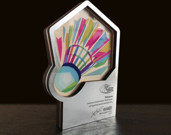 May include: A silver award plaque with a colorful badminton shuttlecock design. The plaque reads "Deklaracija Lietuvos badmintono federacijai uz aigarmeti bendradarbiavima" and is signed "Sportas" with the name "Marius Babrauskas" and the year "2020".