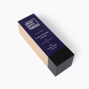 May include: A wooden plaque with a black base and a clear acrylic insert. The insert has a purple background with white text that reads "This certifies: Custom Energy Limited as a Certified Partner of ESC Energy Supply Company."
