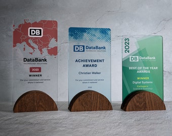 May include: Three clear acrylic award plaques with wooden bases. The plaques feature a blue, green, and red design with the text "DataBank Technology Solutions" and "2023". The awards are for "Achievement Award", "Best of the Year Awards", and "Winner".