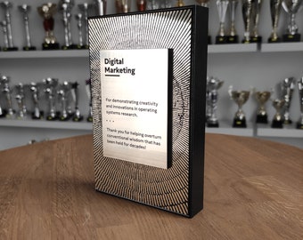 Könnte beinhalten: Eine rechteckige Auszeichnung mit schwarzem Rahmen und goldfarbener Platte. Die Platte trägt die Worte "Digital Marketing" und eine Botschaft über Kreativität und Innovation. Der Hintergrund weist ein radiales Design auf.