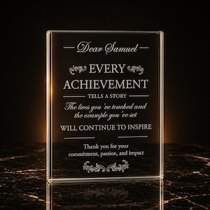 May include: A rectangular clear glass award plaque featuring etched white text that reads: Dear Samuel, EVERY ACHIEVEMENT TELLS A STORY, The lives you've touched and the example you've set WILL CONTINUE TO INSPIRE, Thank you for your commitment, passion, and impact.