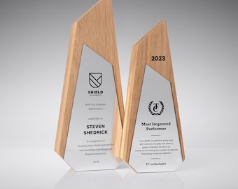May include: Two wooden and silver awards. The left award says "SHIELD INVESTMENTS" and "STEVEN SHEDRICK" with the text "In recognition of 10 years of her dedicated service". The right award says "Most Improved Performer" and "TC technologies".
