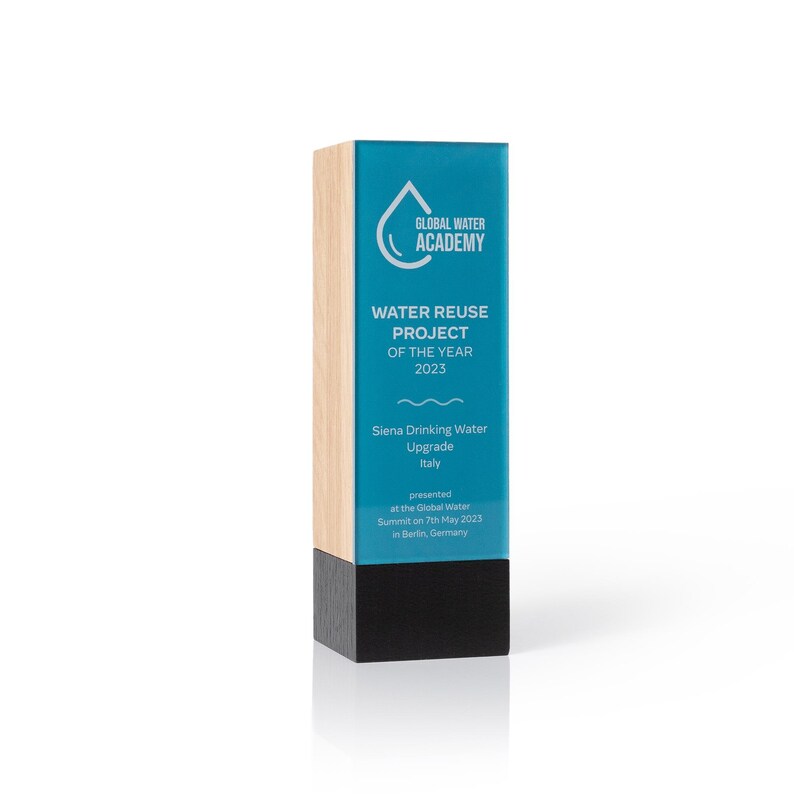 May include: A rectangular award trophy featuring a light wood side, a black base, and a teal front panel. The text reads Global Water Academy, Water Reuse Project of the Year 2023, Siena Drinking Water Upgrade Italy, presented at the Global Water Summit.