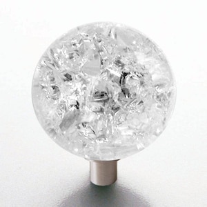 Könnte beinhalten: Ein klarer Glasknopf mit einem strukturierten, rissigen Eisdesign. Der Knopf ist an einer silbernen Metallbasis befestigt.