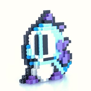 Peut inclure: Un personnage pixelisé bleu et blanc avec des accents violets. Le personnage est fait de petits blocs de plastique et est une représentation 3D d'un personnage de jeu vidéo.