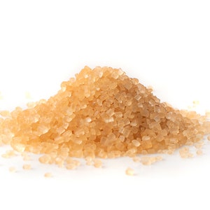 May include: A close-up of a pile of light brown granulated sugar crystals.