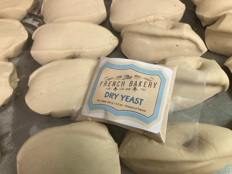 May include: A white bag of dry yeast with a blue and white label that reads "The French Bakery Est. 1964 Dry Yeast Dry Yeast 100 g / 3.5 oz - Product of France".