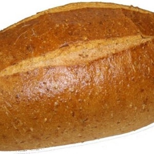 May include: A loaf of brown bread with a slightly darker brown crust. The bread has a long, oval shape and is slightly flattened on the top.