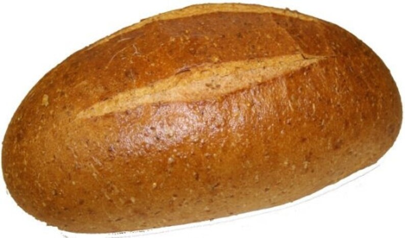 May include: A loaf of brown bread with a slightly darker brown crust. The bread has a long, oval shape and is slightly flattened on the top.