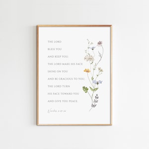 May include: A framed print featuring a watercolour illustration of wildflowers and a bible verse from Numbers 6:24-26. The verse reads: "The Lord bless you and keep you: The Lord make his face shine on you and be gracious to you; The Lord turn his face toward you and give you peace."