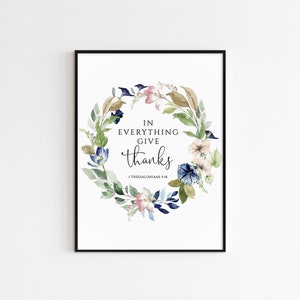 Könnte beinhalten: Ein Aquarelldruck mit einem floralen Kranz in Blautönen, Grün und Rosa. Der Kranz umgibt den Text "In allem seid dankbar 1 Thessalonicher 5,18".