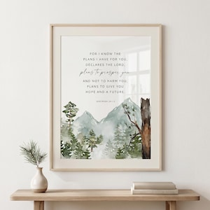 May include: A framed wall art print featuring a watercolor landscape of green mountains and pine trees. The text reads: FOR I KNOW THE PLANS I HAVE FOR YOU, DECLARES THE LORD, plans to prosper you AND NOT TO HARM YOU, PLANS TO GIVE YOU HOPE AND A FUTURE. JEREMIAH 29:11.