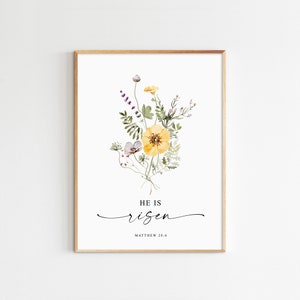 May include: A watercolor print with a bouquet of yellow and white flowers with green leaves and stems. The text "HE IS risen" and "MATTHEW 28:6" is below the flowers.