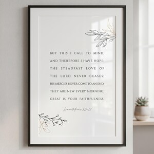 Pode incluir: Uma impressão de parede emoldurada com texto preto em fonte serifada sobre fundo branco. O texto diz: BUT THIS I CALL TO MIND, AND THEREFORE I HAVE HOPE: THE STEADFAST LOVE OF THE LORD NEVER CEASES: HIS MERCIES NEVER COME TO AN END: THEY ARE NEW EVERY MORNING: GREAT IS YOUR FAITHFULNESS. Lamentations 3:21-23. Ilustrações delicadas de folhas em linhas pretas e douradas decoram os cantos superior direito e inferior esquerdo.