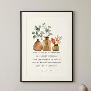 Puede incluir: Una lámina enmarcada con tres jarrones de cristal llenos de eucalipto verde, ramas secas y flores rosas. Bajo la ilustración, el texto dice: Therefore, my beloved brothers, be steadfast, immovable, always abounding in the work of the Lord, knowing that in the Lord your labor is not in vain. 1 Corinthians 15:58.