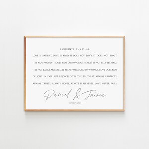 May include: A framed print with a white background and black text. The text is a quote from the Bible, 1 Corinthians 13:4-8, about love. The print also includes the names "Daniel & Jaime" and the date "April 29, 2023".