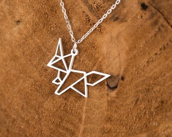 Peut inclure: Un collier avec un pendentif en forme de renard origami en argent sur une chaîne en argent. Le collier est présenté sur une surface en bois.