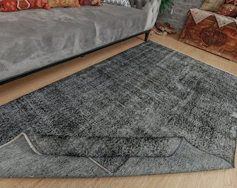 Pode incluir: Um tapete cinza escuro com um padrão sutil. O tapete é feito de um material macio e felpudo e tem um visual ligeiramente desgastado.