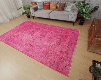 May include: A pink vintage rug with a faded floral pattern. The rug has a distressed look and is perfect for adding a touch of bohemian style to any room.