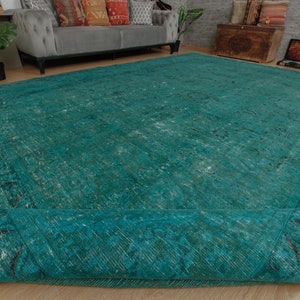May include: A teal blue vintage rug with a faded pattern and a fringed edge. The rug is rolled up and the edge is visible.