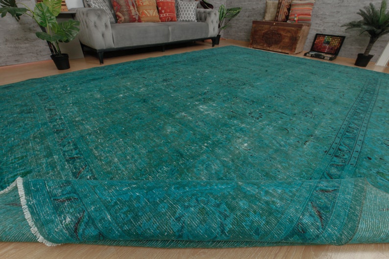 May include: A teal blue vintage rug with a faded pattern and a fringed edge. The rug is rolled up and the edge is visible.