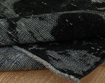Pode incluir: Close-up de um tapete com padrão preto e branco com trama texturizada. O tapete está dobrado ao meio, mostrando o avesso do tecido.
