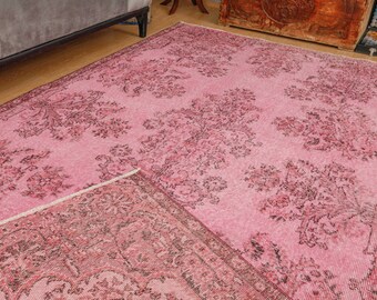 May include: A pink vintage rug with a floral pattern. The rug has a faded look and is made of a soft, woven material.