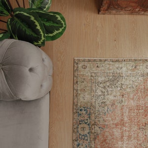 Puede incluir: Un sof&aacute; gris claro capiton&eacute; con una alfombra estampada en tonos beige, marr&oacute;n y azul. La alfombra tiene un aspecto descolorido y vintage.