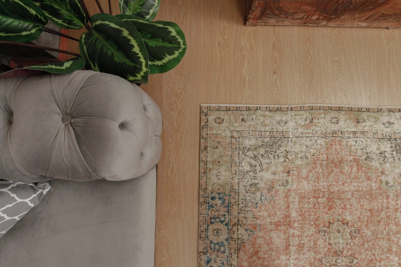 Puede incluir: Un sof&aacute; gris claro capiton&eacute; con una alfombra estampada en tonos beige, marr&oacute;n y azul. La alfombra tiene un aspecto descolorido y vintage.