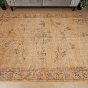 May include: A vintage-style rug with a beige background and a floral pattern in shades of brown, red, and blue. The rug has a faded, distressed look, giving it a unique and antique feel.