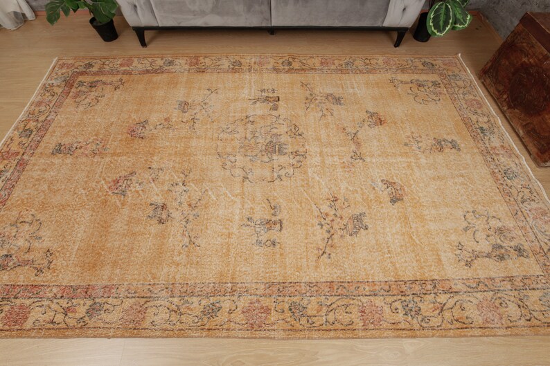 May include: A vintage-style rug with a beige background and a floral pattern in shades of brown, red, and blue. The rug has a faded, distressed look, giving it a unique and antique feel.