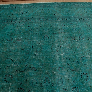 May include: A teal blue rug with a traditional Persian design. The rug has a faded look and features intricate floral patterns.