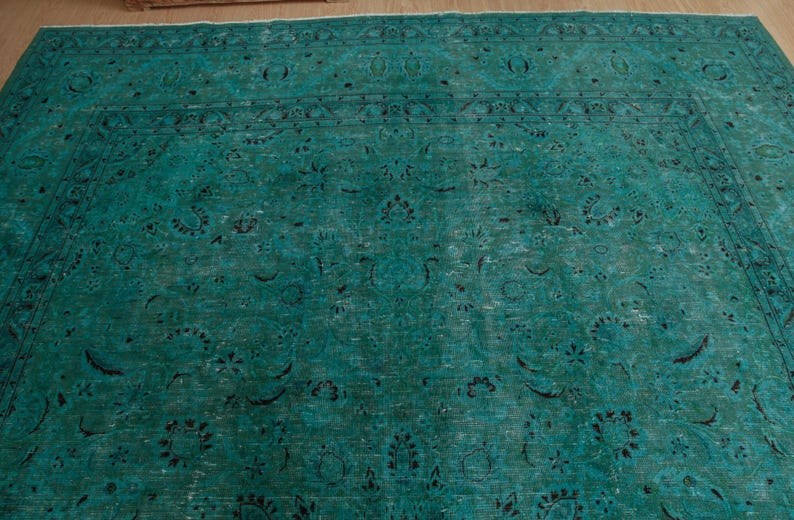 May include: A teal blue rug with a traditional Persian design. The rug has a faded look and features intricate floral patterns.