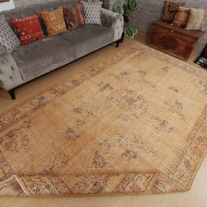 May include: A vintage-style rug with a beige background and a floral pattern in shades of brown, red, and blue. The rug has a fringed edge and is laid out on a wooden floor.