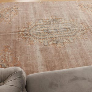 May include: A light brown vintage rug with a faded floral pattern. The rug has a distressed look and is perfect for adding a touch of vintage charm to any room.