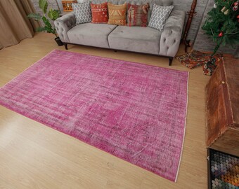 May include: A pink vintage distressed rug with a faded pattern. The rug is laid out on a wooden floor.