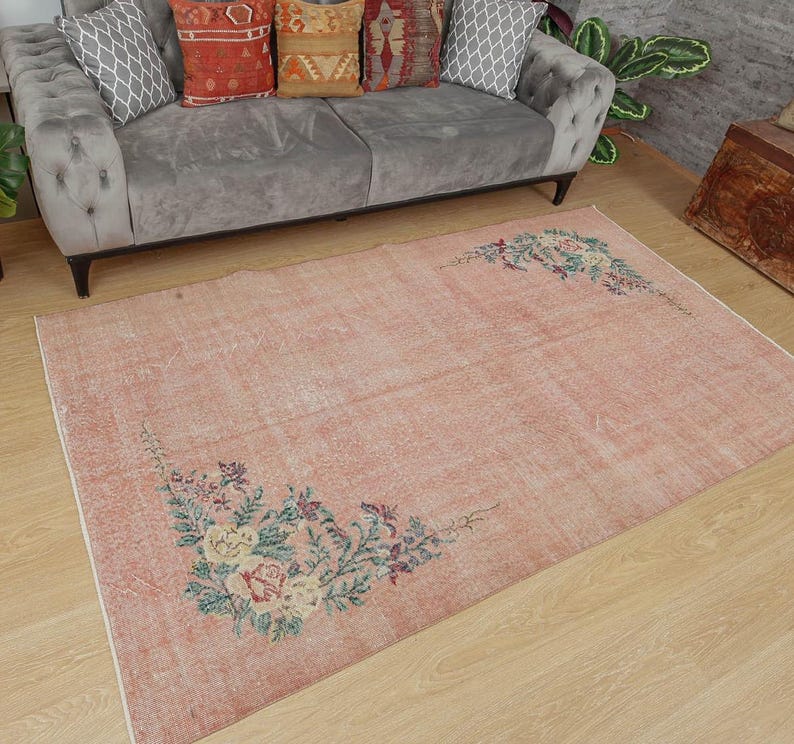 May include: A light pink vintage rug with a floral design. The rug has a faded, distressed look and features a floral pattern in shades of green, pink, and yellow.