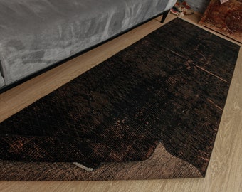 May include: A black and brown area rug with a distressed, vintage look. The rug has a subtle pattern and is made of a soft, durable material.
