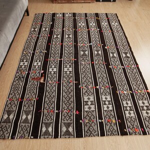 May include: Black and white striped rug with a geometric pattern. The rug has a fringed border and is made of a soft, woven material.