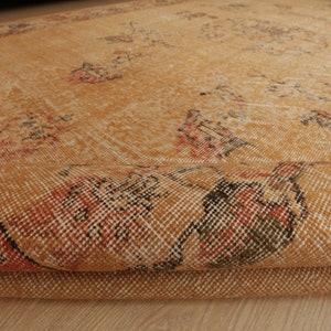 May include: A folded, tan and orange rug with a woven pattern. The rug has a distressed look and is made of a soft, natural material.