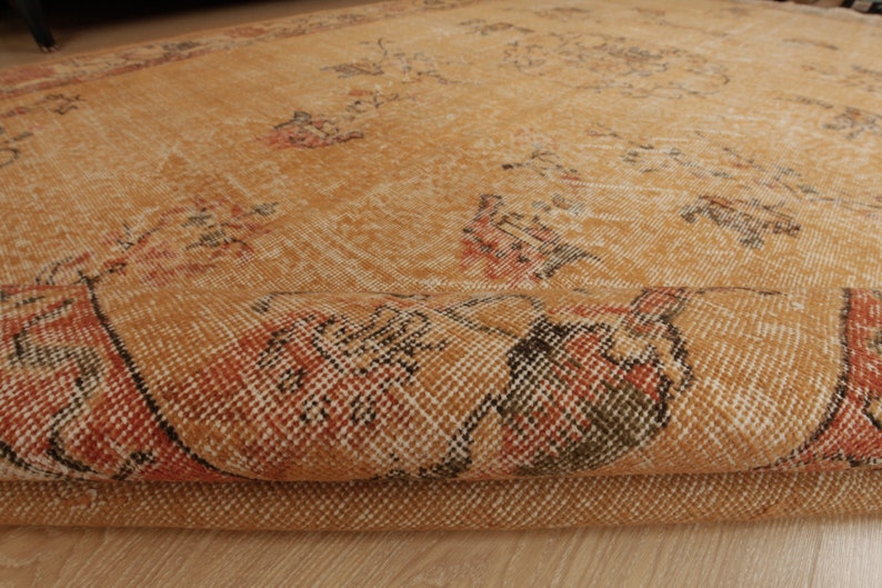 May include: A folded, tan and orange rug with a woven pattern. The rug has a distressed look and is made of a soft, natural material.