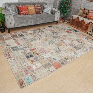 Op de afbeelding: Een groot, rechthoekig patchwork tapijt met een crème achtergrond en kleurrijke vierkanten met verschillende patronen en kleuren. Het tapijt is gemaakt van geweven stof en heeft een verweerde, vintage uitstraling.