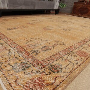May include: A vintage-style rug with a beige background and a floral pattern in shades of orange, red, and brown. The rug has a faded look, giving it a distressed and antique feel.