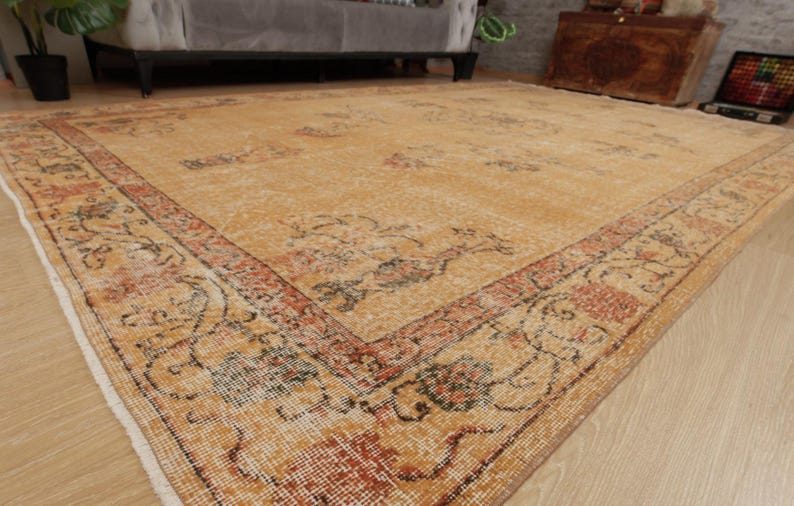May include: A vintage-style rug with a beige background and a floral pattern in shades of orange, red, and brown. The rug has a faded look, giving it a distressed and antique feel.