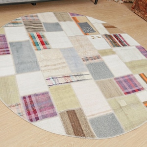 Può includere: Tappeto rotondo in patchwork con sfondo bianco e quadrati colorati. Il tappeto è realizzato con diversi tessuti e trame, creando un look unico ed eclettico.