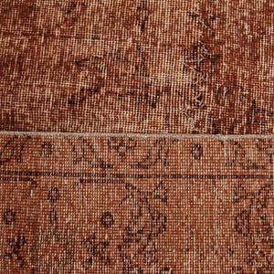 May include: A woven rug featuring a deep rust-brown color palette with a distressed, weathered texture. The surface displays a repeating pattern of dark brown linear motifs and geometric shapes arranged in a structured border and field design.