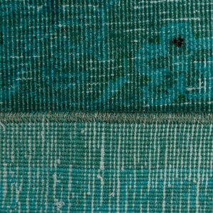May include: Close-up of a teal blue woven rug with a fringe border. The rug has a textured surface and a subtle pattern.